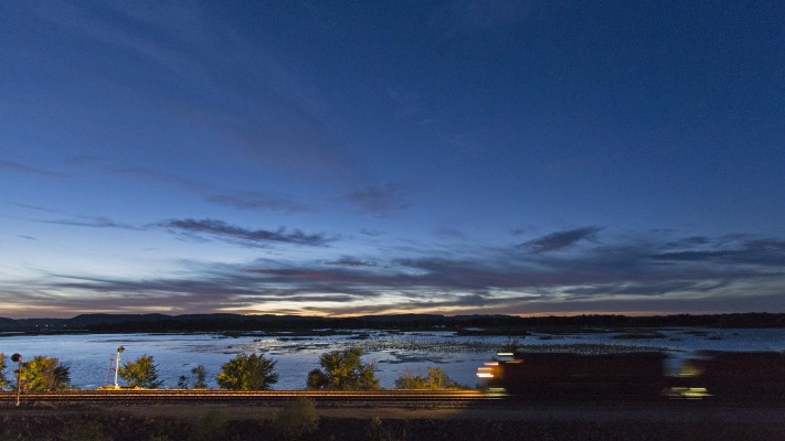 BNSF Railway eastbound automobile train V-TACLPC running along the Mississippi River at Stoddard, Wisconsin, at twilight on October 8, 2013.