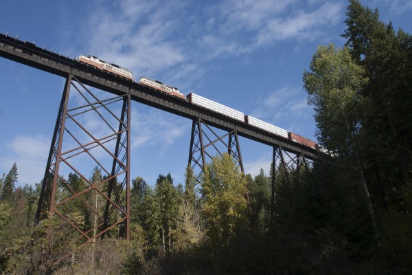 St. Maries River Railroad's outbound Plummer Turn crosses the high steel of Peedee Trestle on the former Milwaukee Road main line in northern Idaho. The train is hauling finished lumber from the Potlatch mill in St. Maries to the Union Pacific interchange in Plummer.