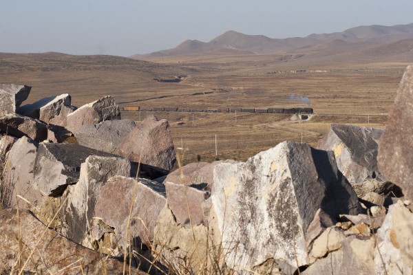 Viewed from a hill at the brickworks just east of the city, an eastbound Jitong Railway freight train departs Daban, Inner Mongolia, China, in November 2005.