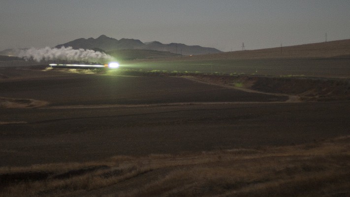 The Jitong Railway's westbound local passenger train charges up the grade west of Tianshan, Inner Mongolia, China, by the light of the full moon in November 2005.