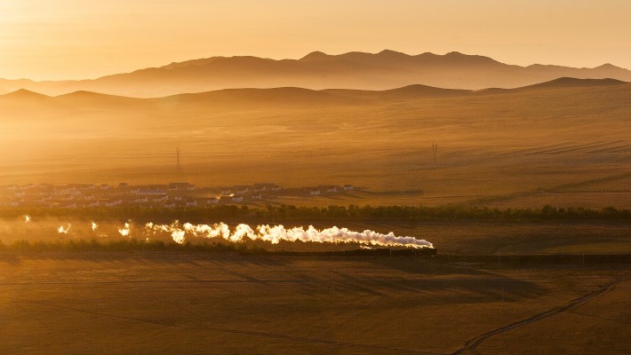 Just after sunrise on October 4, 2005, a short westbound freight train steams though Baomutu, Inner Mongolia, China, on the Jitong Railway.