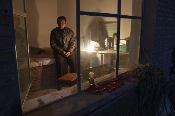 The Jitong Railway's crossing gatekeeper at Baomutu, Inner Mongolia, China, rests in his shanty on a mild October night in 2005.