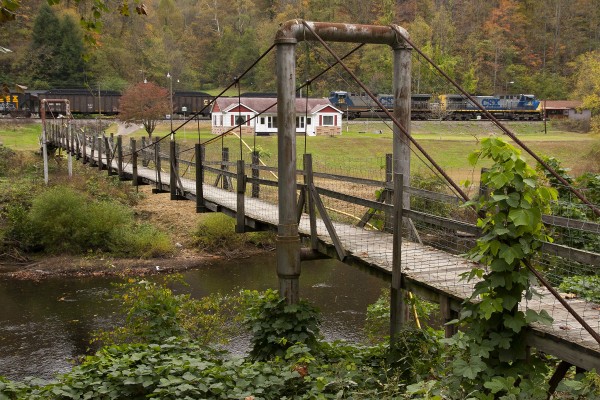 A CSX unit coal train passes a suspension bridge on the Big Coal Subdivision in southern West Virginia. The bridge provides the only access to residents living across the river.