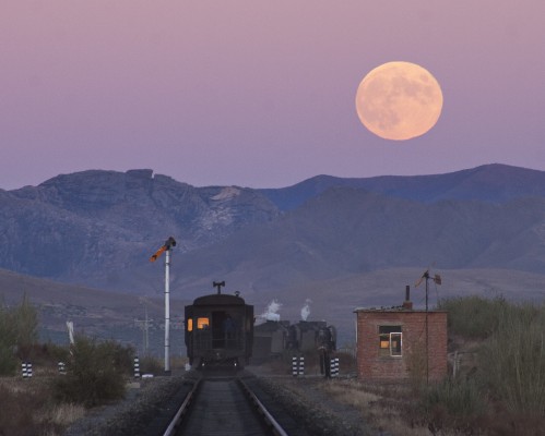 The harvest moon rises above an eastbound Jitong Railway freight train near Chagganhada, Inner Mongolia, China, in October 2005.