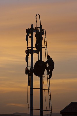 Jitong Railway workers hang new color light signals next to the semaphores at Baomutu, Inner, Mongolia, China, as the sun sets on a fall day in 2005.