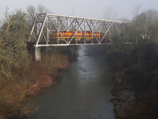 Portland and Western's American Turn freight train rolls south over the Calapooia River in Albany, Oregon, as the morning sun cuts through the fog on February 3, 2009.