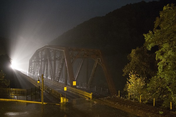 Headlights of a CSX local freight train shine across the New River at Thurmond, West Virginia, on a wet night in October 2007.