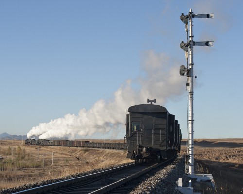 A westbound Jitong Railway freight train steams away from Gulumanhan, Inner Mongolia, China, behind two QJ 2-10-2 steam locomotives in October 2005.