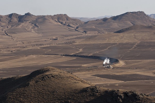 Two QJ steam locomotives lead a westbound Jitong Railway freight train through a sweeping curve in the mountains just east of Lindong, Inner Mongolia, China, in November 2005.