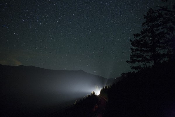 Stars fill the clear night sky above Cruzatte, Oregon, high in the Cascade Mountains, as a northward Union Pacific freight train shines its light through the fir trees after midnight on May 23, 2009.