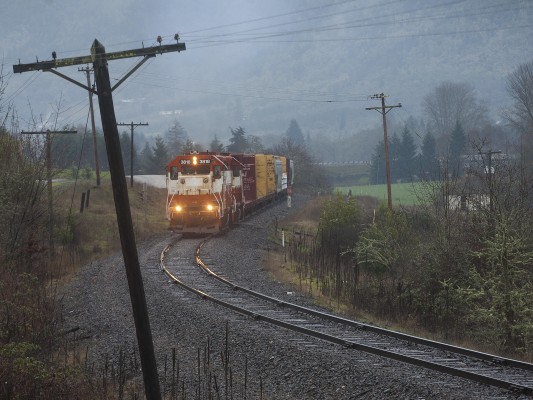 Central Oregon and Pacific Railroad freight train framed by leaning power poles north of Riddle, Oregon, on February 1, 2010.