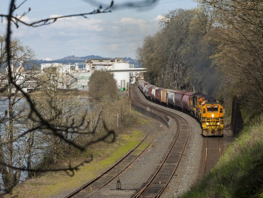 Portland and Western Job 663 rolls south on the Union Pacific main line along the Willamette River in Oregon City, Oregon, on April 8, 2011. The track at far left heads into the Blue Heron paper mill in the background.