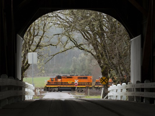 Portland and Western's Toledo Hauler freight train rolls east at Harris, Oregon, framed by the covered bridge over the Marys River on the early spring day of March 31, 2011.