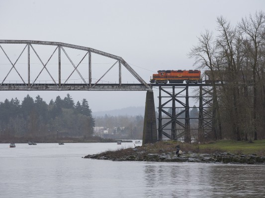 Portland and Western switcher crossing the Willamette River between Milwaukie and Lake Oswego, Oregon, with a single covered hopper car to take back to the yard in Tigard on February 18, 2011. The boats carry sturgeon fisherman.