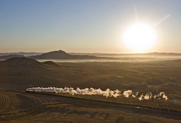 Westbound freight train behind a single QJ steam locomotive charging up the grade out of Tianshan (Chabuga), Inner Mongolia, China, just after sunrise on October 21, 2005.