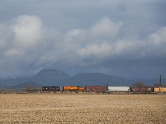 Portland and Western's American Turn rolls north near Junction City, Oregon, under swirling clouds on the winter solstice in 2009. GP9 locomotive 1801 leads the train.