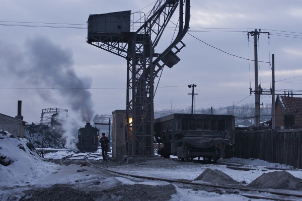 A worker clears a path at the Nanchang engine terminal as an SY-class 2-8-2 takes water in the background in Chengzihe on the Jixi Coal Railway.