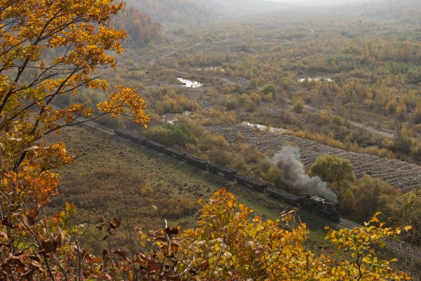 A fleeting sun break on an otherwise gloomy day illuminates an eight-car loaded coal of the Huanan Forestry Railway returning to Lixin from the mines at Hongguang on September 29, 2005. The valley here bears scars from gold mining activities.