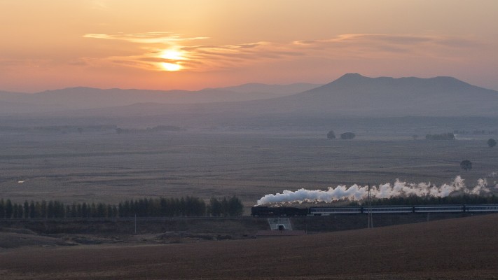 Jitong Railway morning local passenger train steaming through Gulumanhan at sunrise in October 2005.