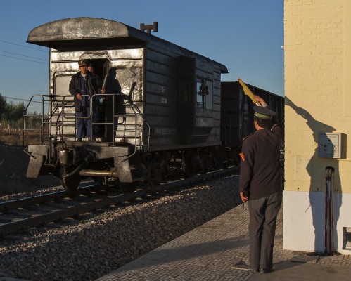 Jitong Railway workers exchange flag waves as a westbound freight train passes a road crossing near Xigou, Inner Mongolia, on October 2, 2005.