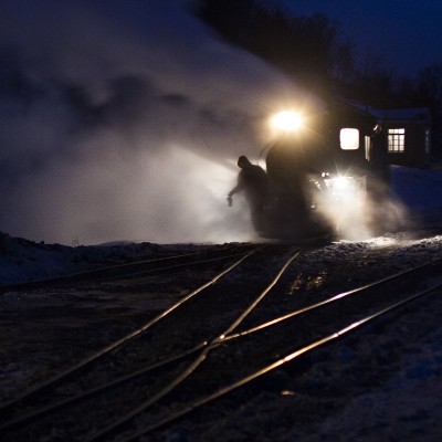 A trainman of the Huanan Forestry Railway rides the pilot of a narrow-gauge 0-8-0 C2 steam locomotive while preparing a loaded coal train for departure out of Lixin in the predawn darkness of December 2, 2005.
