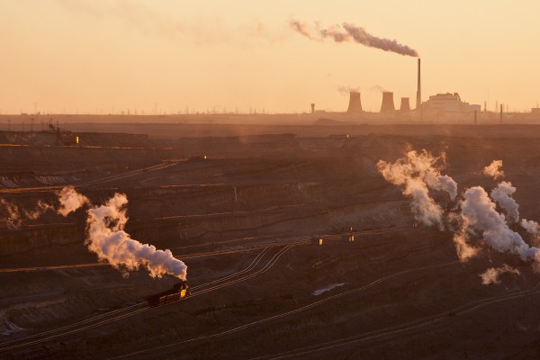 Steam trains at the Zhalainuoer open pit coal mine with the coal-fired power plant in the distance.