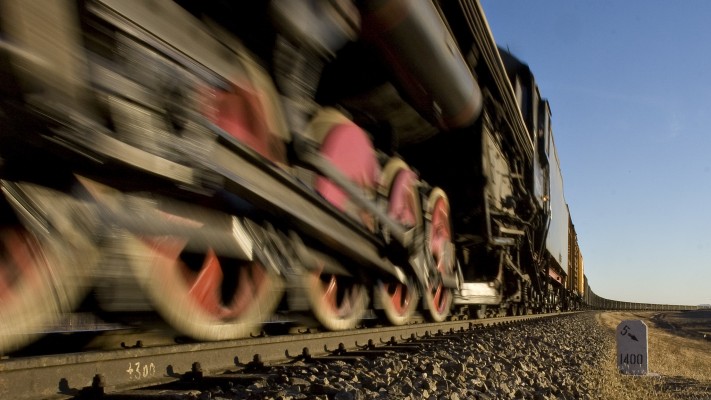 The red driving wheels of a QJ 2-10-2 steam locomotive on the Jitong Railway flash by on an eastbound freight train approaching Gulumanhan in October 2005.