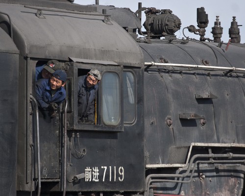 The engineer and two fireman of Jitong Railway QJ no. 7119 look back from their cab prior to departing Daban with an eastbound freight train in November 2005.