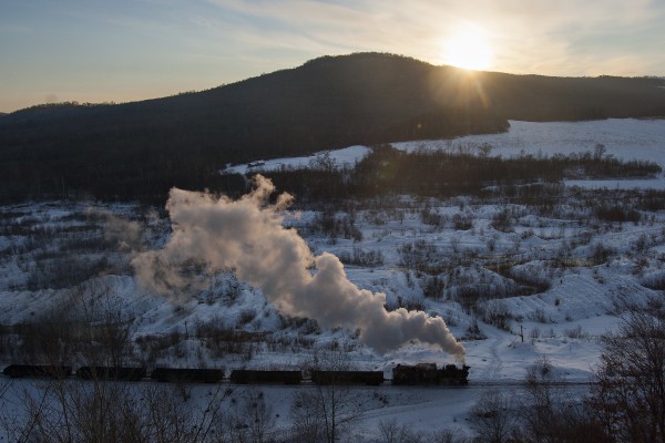 As the sun sets over the hills east of Lixin, Heilongjiang, China, a narrow-gauge 0-8-0 C2 steam locomotive leads another eight-car loaded coal train back from the mines at Hongguang on December 1, 2005.