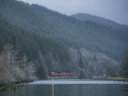 Portland and Western's Toledo Hauler freight train rolls west along the Yaquina River near its destination of Toledo, Oregon, as twilight settles over the Coast Range mountains on March 7, 2010.