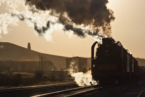 The setting sun outlines the pagoda and an eastbound Jitong Railway freight train at Lindong, Inner Mongolia, China, in November 2005.