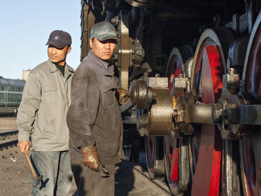 Two Jitong railwaymen work on the running gear of a QJ steam locomotive at Daban.