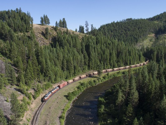 The St. Maries River Railroad's inbound Clarkia Logger brings a trainload of logs down its namesake near milepost 17. The single boxcar behind the two ex-Milwaukee Road GP9s is a load of garnet from the plant in Emerald Creek, Idaho.