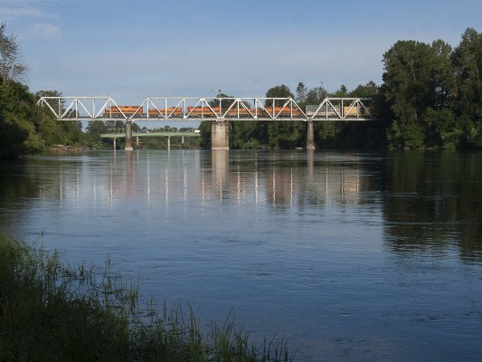 The morning sun and the placid Willamette River greet Portland and Western's Toledo Hauler in Albany, Oregon, following the train's mostly overnight run to Toledo and back.