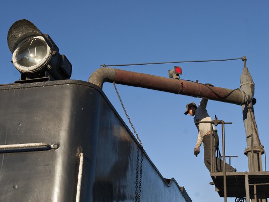 Jitong Railway worker swings the water column over the tender of a QJ steam locomotive in Daban.