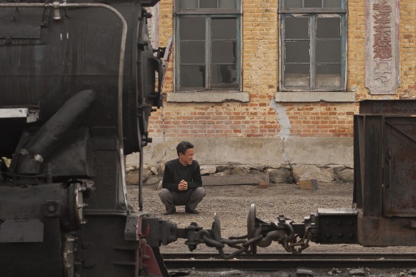 The station agent in the village of Xiahua inspects a work train on the foggy morning of September 27, 2005. Couplers on the narrow-gauge Huanan Forestry Railway consisted of a buffer and two chains.