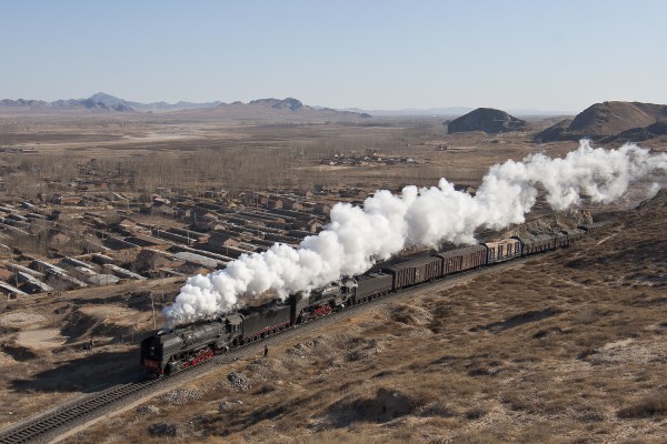 Two QJ steam locomotives lead a westbound freight train into Lindong, Inner Mongolia, China, on a clear day in November 2005.