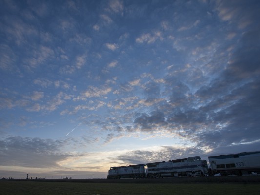 Amtrak's <i>Coast Starlight</i> passenger train and a jet both head south just after sunset in western Oregon's Willamette Valley on January 2, 2010.