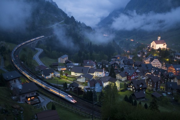 A double set of tilting trains descends through the middle level of track at Wassen, Switzerland, with a late evening passenger service as fog rolls up the Reuss Valley and the famous Church of St. Gallus glows in the darkness. The notion of photographing this scene at twilight is what compelled me to visit the Gotthard Railway; both the fog and the overall experience vastly exceeded my expectations.