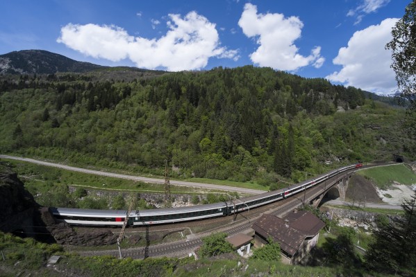 With extra cars for holiday weekend traffic, an InterRegio passenger train rolls south over the Polmengo Viaduct and Ticino River near Faido, Switezerland, behind an Re 460 electric locomotive.