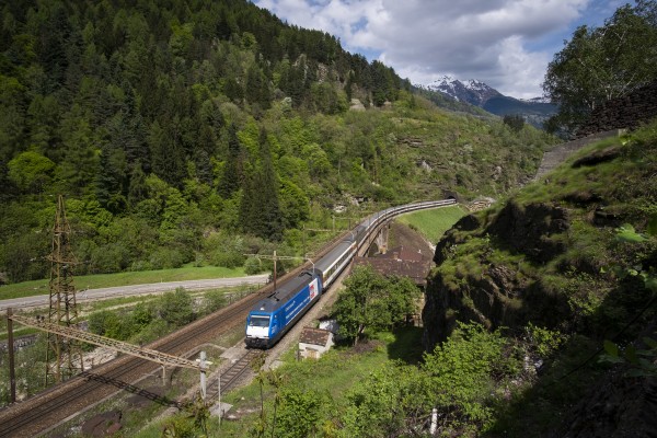 Re 460 locomotive in special blue paint for the 2016 opening of the new Gotthard Base Tunnel leads an InterRegio passenger train north near Faido.