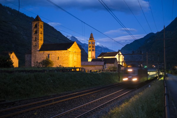 Giornico's medieval churches of San Nicola and San Michele glow at twilight as InterRegio passneger train no. 2442 heads north.