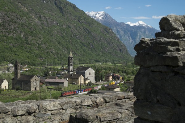 Three electric locomotives lead a container train north through Giornico, Switzerland, on the southern approach of Gotthard Pass. The view is from the hilltop church-fortress Santa Maria del Castello, which dates from the eleventh century. The train is passing the twelfth-century Church of San Nicola at far right and the thirteenth-century Church of San Michele.