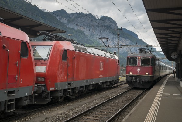 InterRegio train 2331 from Basel to Locarno arrives at Erstfeld as two Deutsche Bahn 185 class electrics wait to take a freight north.