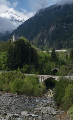 The Meienreuss flows into the River Reuss at Wassen just below the 1733 Catholic church. The old highway crosses the Meienreuss in the foreground, with two levels fo the railway visible beyond.