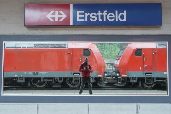 A reflective window in the Erstfeld station presented a self-portrait opportunity too good to refuse, especially with the red Deutsche Bahn class 185s matching my rain jacket.