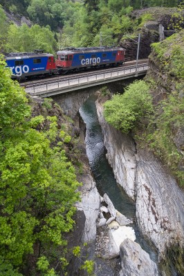 A pair of Swiss Federal Railways electrics in the blue and red Cargo scheme cross the Ticino River in the Piottino Gorge.