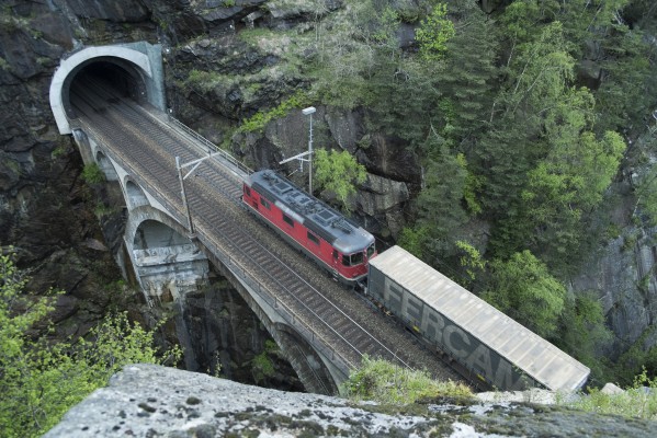 A Swiss Federal Railways Re 420 electric locomotive pushes on the rear a container train south crossing the Upper Meienreuss Bridge at Wassen, Switzerland.