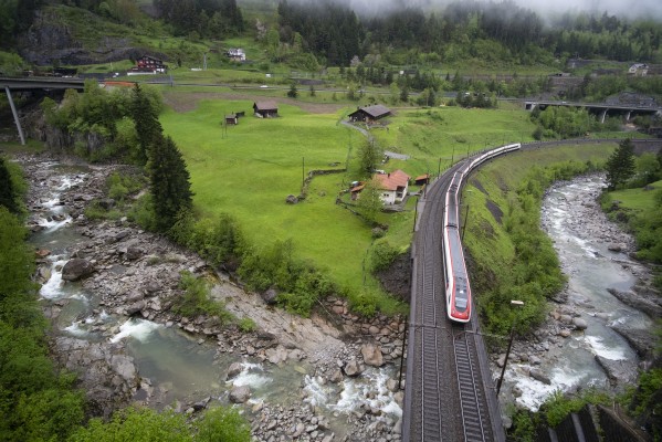 An ICN tilting train leans into the Wattingen curve as it rolls across the River Reuss just above Wassen.