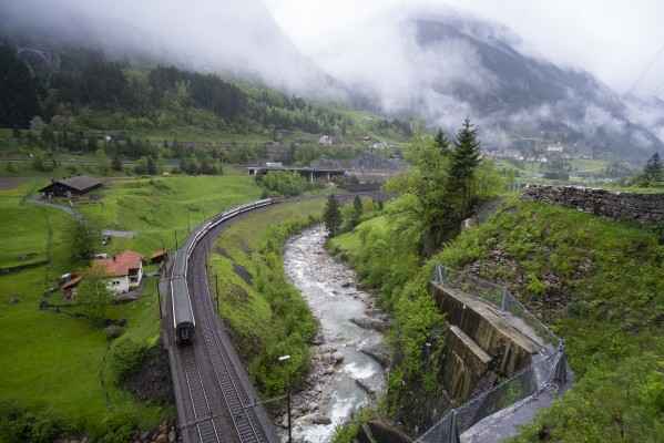 An InterRegio train north rolls down the Reuss as clouds shroud the hills around Wassen.